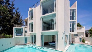 Een modern huis met twee verdiepingen en een zwembad ervoor.