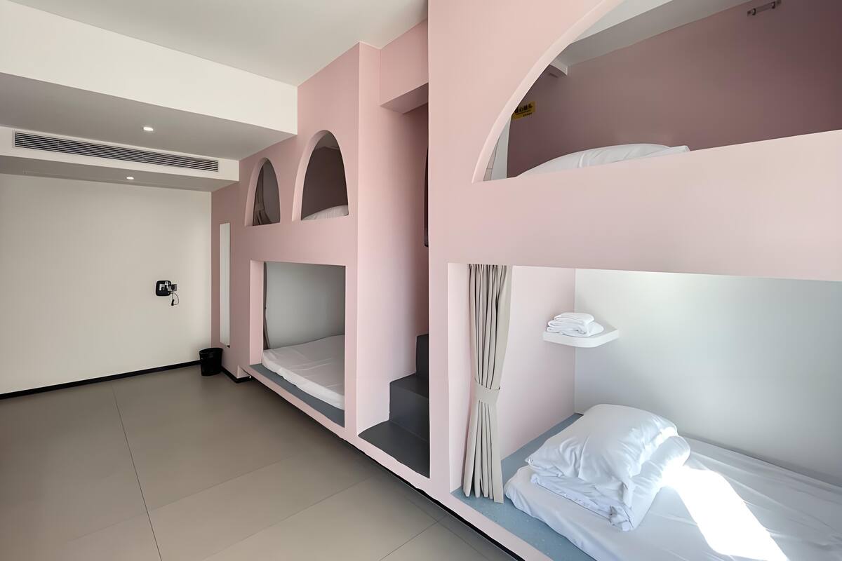 A bunk bed room with a white ceiling, a small shelf, and a curtain.