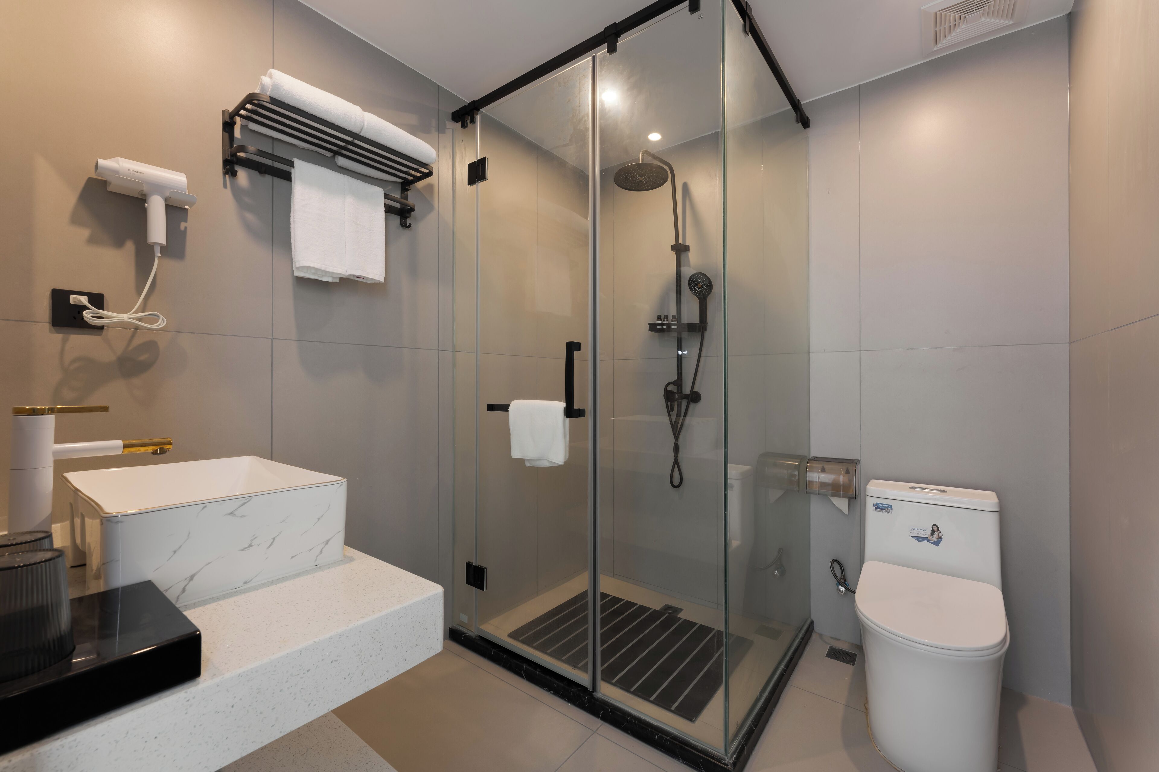 Ein modernes Badezimmer mit einer gläsernen Dusche, einer weißen Toilette und einem мраморном Waschbecken.