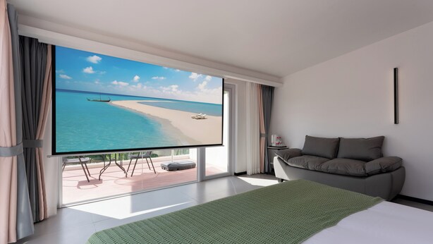 Een moderne hotelkamer met een groot raam, een bed, een slaapbank en een flatscreen televisie waarop een uitzicht op het strand te zien is.