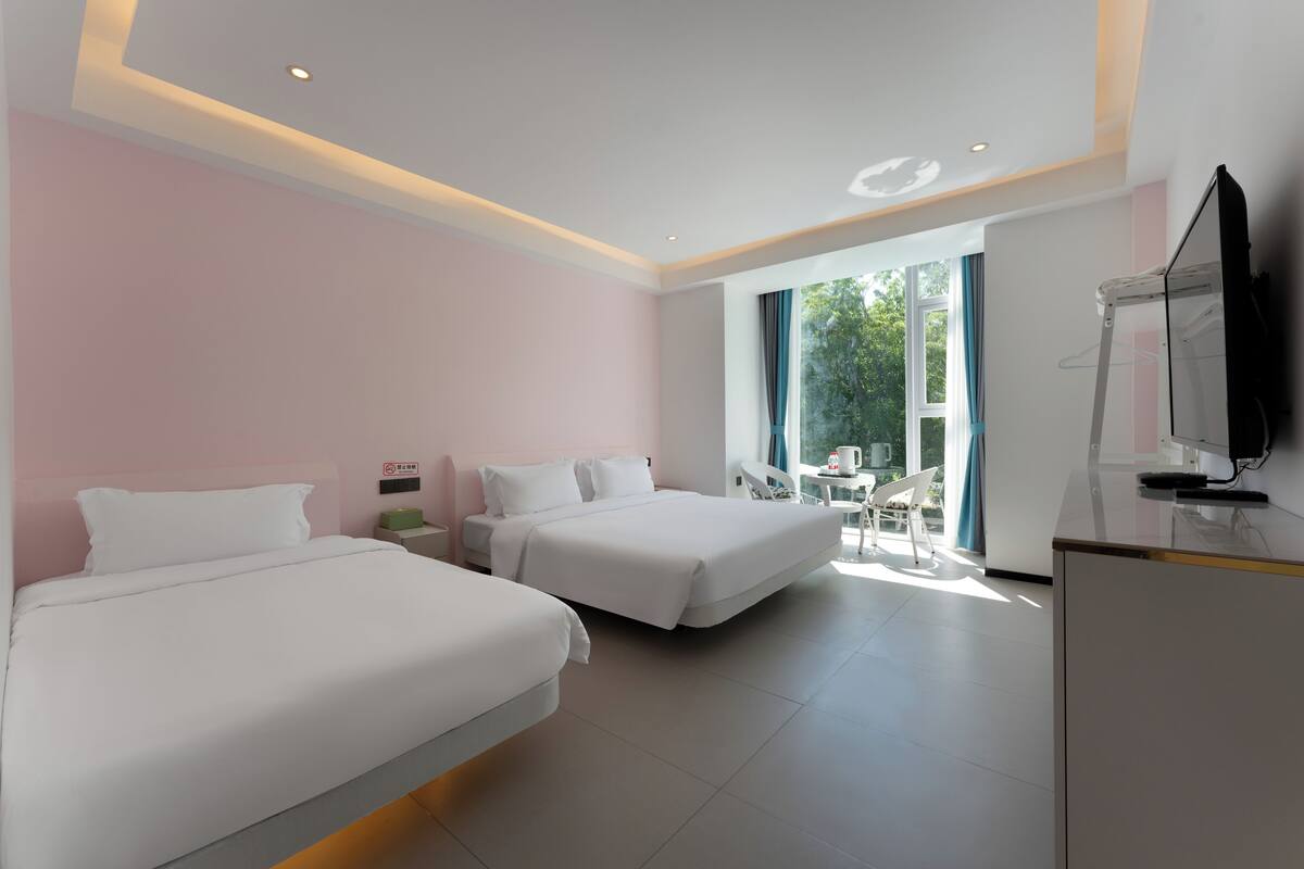A modern hotel room with two beds, a desk, and a TV.