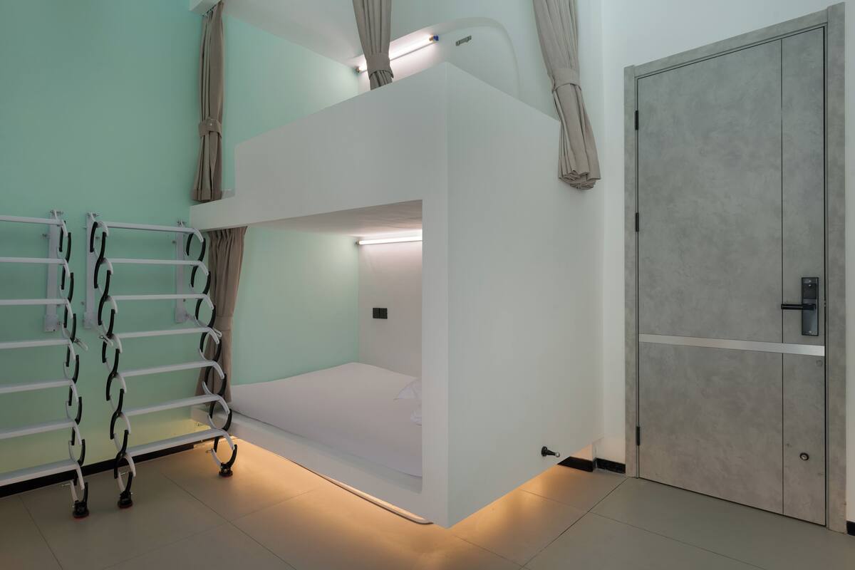 A bunk bed room with a ceiling fan, a wardrobe, and a curtain rod.