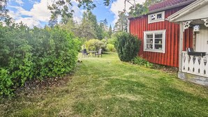 A red house with a white fence, a lawn, and a table with chairs. - Awesome home in Skillingaryd with WiFi (Skillingaryd)