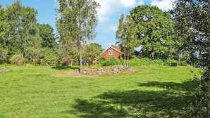 A grassy field with a red house surrounded by trees. - Awesome home in Skillingaryd with WiFi (Skillingaryd)
