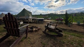 A campsite with tents, wooden furniture, and a rocky area. - Cosmo Glamping (Valle de Guadalupe)