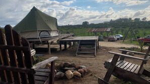 A campsite with a green tent, wooden benches, and a fire pit. - Cosmo Glamping (Valle de Guadalupe)