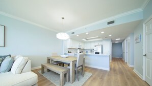 Une cuisine moderne avec des meubles blancs, une table à manger en bois et un îlot central intégré.