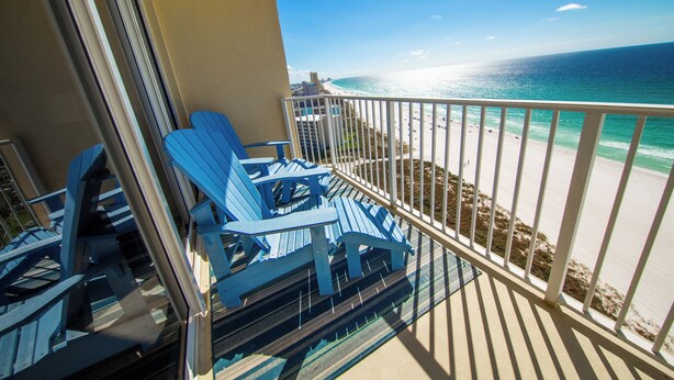 Un balcone con sedie blu che si affaccia su una spiaggia.