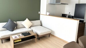 Un salon moderne comprenant un canapé, une table basse et un coin cuisine équipé d’un four à micro-ondes et d’un grille-pain.