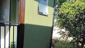 Paret exterior verda amb una finestra, una finestra petita de color blanc i una barana metàl·lica.