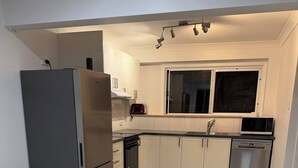 Eine moderne Küche mit weißen Schränken, Edelstahlgeräten und einem großen Fenster.