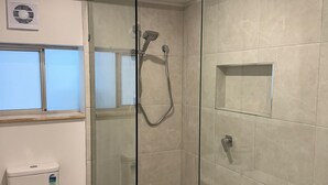 Ein modernes Badezimmer mit einer Glaskabine zur Dusche, Toilette und Bidet.