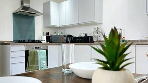 Una cocina moderna con armarios blancos, una campana extractora de acero inoxidable y una encimera de madera.
