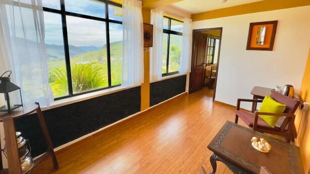 A room with large windows, a wooden floor, a dining table, and a chair. - House of Leisure Holiday Bungalow  (Nuwara Eliya)