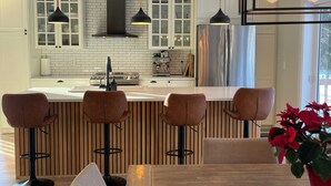 Een moderne keuken met witte kasten, een roestvrijstalen koelkast en een bargedeelte met krukken.