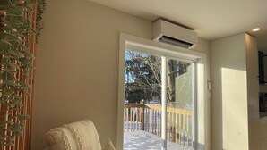 Een moderne woonkamer met een witte bank, een houten vloer en uitzicht op een besneeuwd terras door een glazen deur.