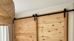 Een kamer met een schuifhouten deur, een geweven lamp en een raam met witte gordijnen.