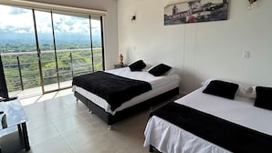 A bedroom with two beds, a large window, and a view of the landscape.