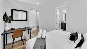 A modern hotel room with a bed, a desk, a chair, and a large mirror. - NEW Modern 1BR in Oak Lawn Dallas With Free Parking + Complimentary EV Charger (Dallas)