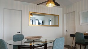 A dining area with a round glass table, four chairs, a ceiling fan, and two wall-mounted mirrors. - Lofty Haven - High/ Harbour Views of Narrows & Signal Hill/ Steps to Downtown (St. John's)