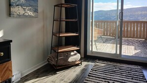 A room with a sliding glass door leading to a balcony with a wooden deck and a mountain view. - Lofty Haven - High/ Harbour Views of Narrows & Signal Hill/ Steps to Downtown (St. John's)
