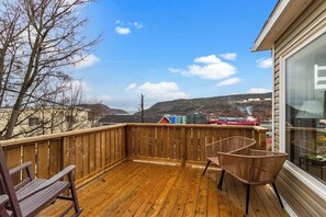 A wooden deck with a view of a ship and hills in the distance.