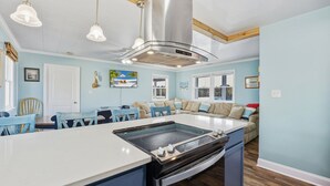 Una cucina moderna con isola centrale, elettrodomestici in acciaio inossidabile e zona pranzo con sedie blu.