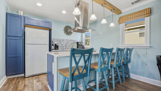 Una cucina con mobili azzurri, una cappa in acciaio inossidabile e un'area pranzo con sedie azzurre.