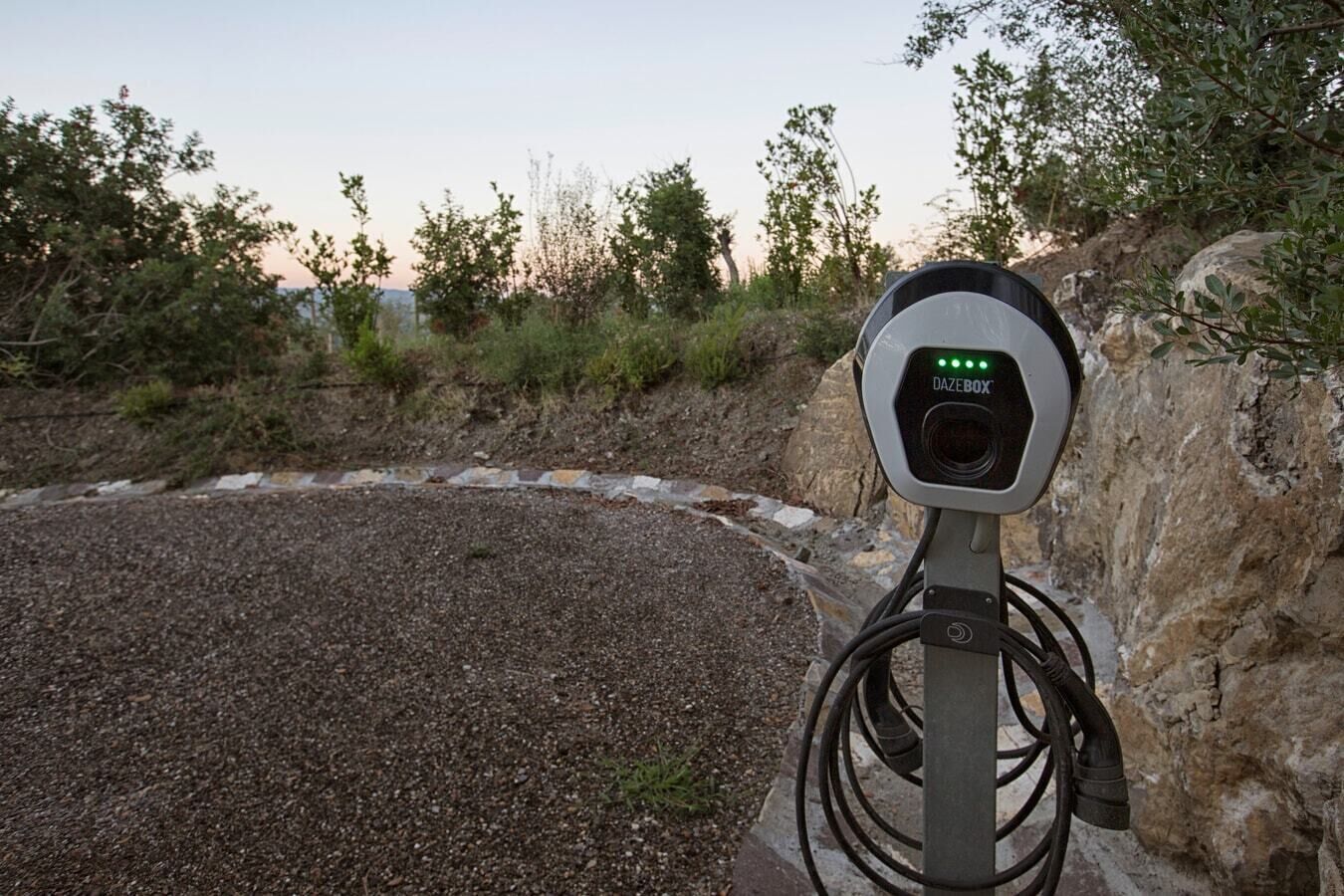 A DAZEBOX charging station with a rocky and vegetated background.