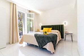 Ein modernes Schlafzimmer mit einem großen Bett, einem grünen gepolsterten Kopfteil und einem Nachttisch mit einer Lampe.