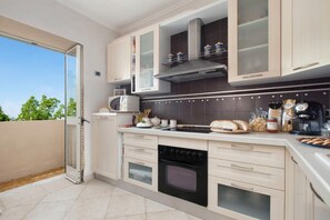 A modern kitchen with white cabinets, a microwave, a stove, and various appliances. - Villa Lume - Private Villa With Pool (Sant'Agata sui Due Golfi)