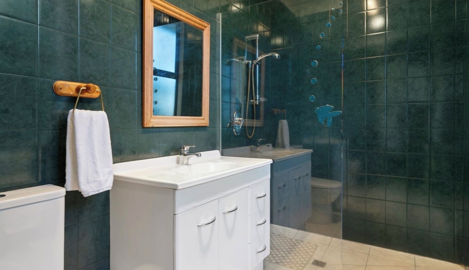 A modern bathroom with a white vanity, a large mirror, and a glass-enclosed shower area.