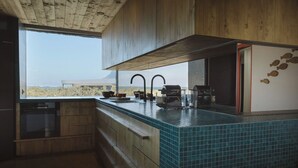 Een keuken met houten kastjes, een blauw betegeld aanrecht en uitzicht op het woestijnlandschap.