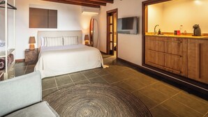 Ein Schlafzimmer mit Bett, Fernseher, einem Holzschrank und einem durchgehenden Türspalt erkennbaren Badezimmer.
