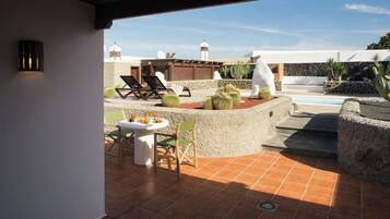 Un patio con mesa y sillas, una piscina y cactus.