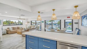 A spacious living area with a large kitchen island, blue cabinets, and pendant lighting. - Waterfront Escape, Private Dock, Cabana Club, Keys Paradise (Key Colony Beach)