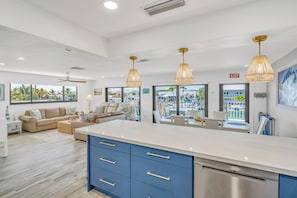 A spacious living area with a large kitchen island, blue cabinets, and pendant lighting. - Top-Rated Waterfront Home Private Dock & Cabana Club (Key Colony Beach)