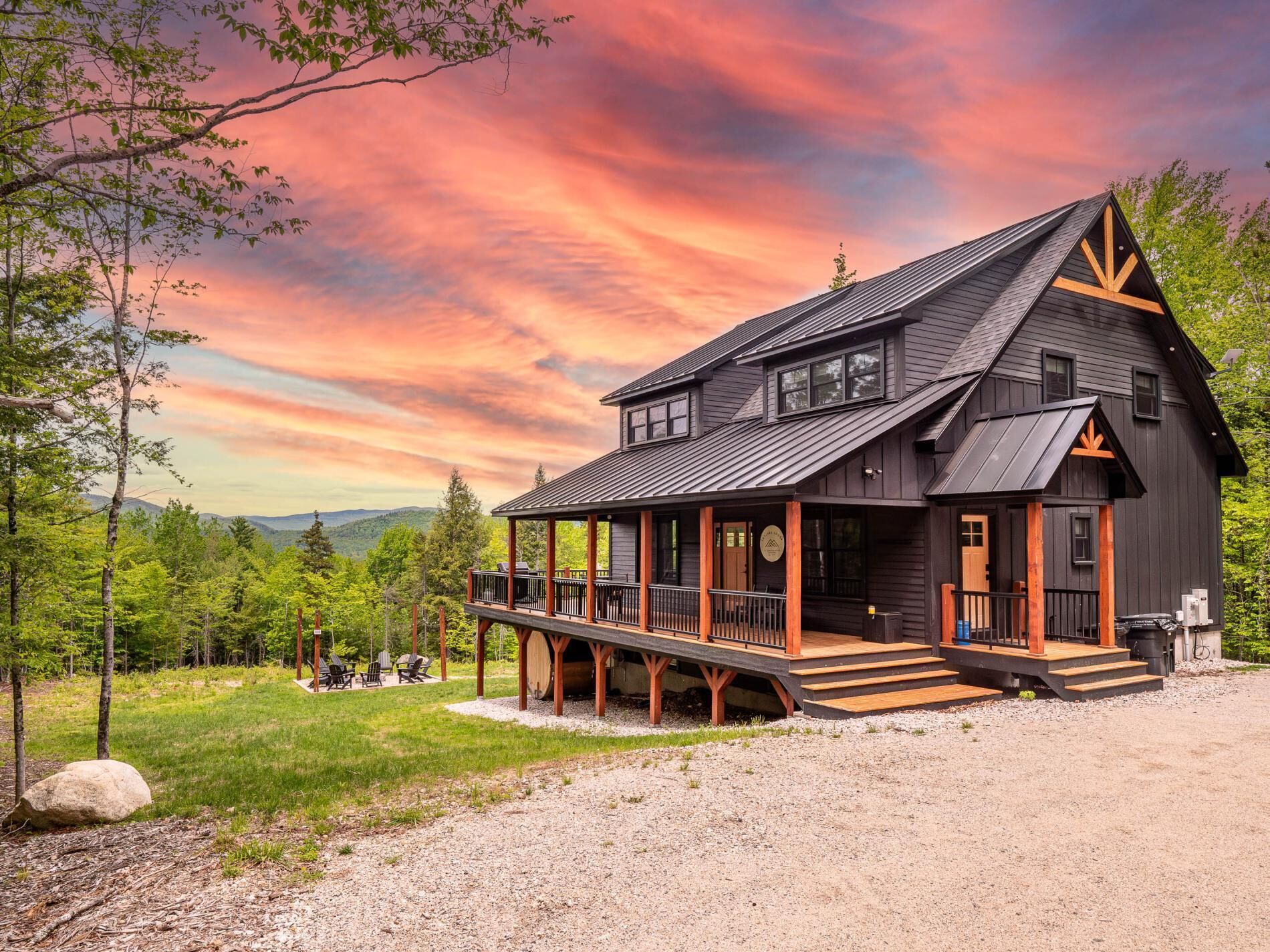 A cabin with a porch, a deck, and a view of the surrounding forest.
