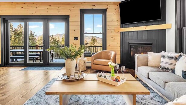 Een moderne woonkamer met een houten vloer, een bank, een salontafel en een open haard.
