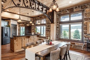 A rustic kitchen with a large island, stone walls, and a view of the outdoors. - Strawberry Mountain Retreat • Sleeps 12 • Direct OHV Access (Fruitland)