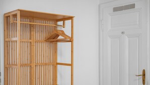 A wooden wardrobe with a hanging rod, a white door with a lock, and a vent above it. - Central | Kitchen | WLAN | 58 sqm (Solingen)