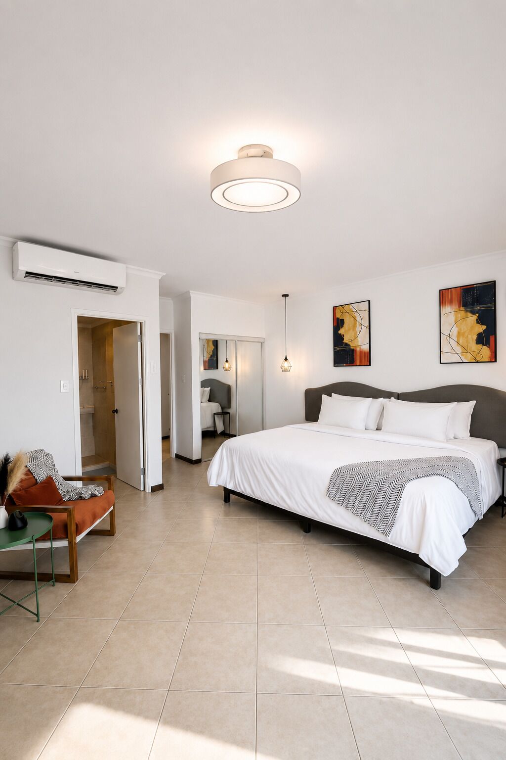 A modern bedroom with a large bed, a bedside table, a chair, and artwork on the walls.
