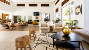 A spacious lobby with a modern design, featuring a large seating area, a coffee table, and a television mounted on the wall. - Gold Coast Aruba  (Noord)