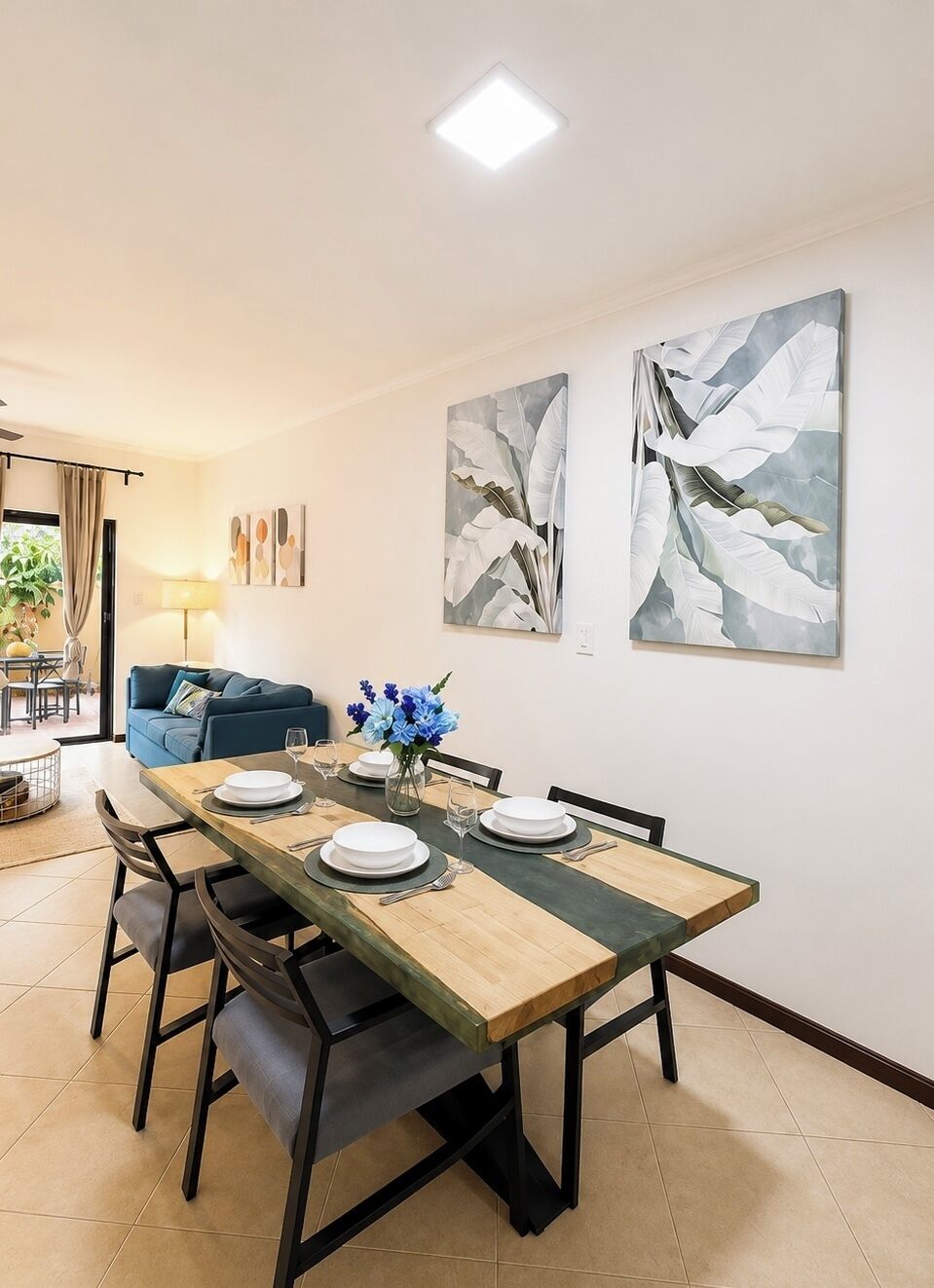 A dining area with a wooden table, chairs, and artwork on the wall.