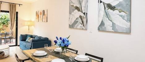 A dining area with a wooden table, chairs, and artwork on the wall.