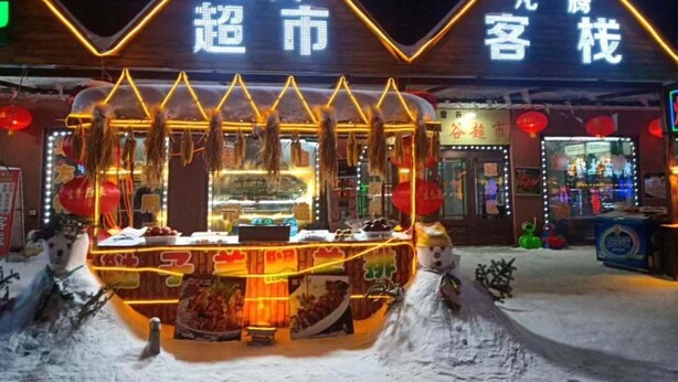 Un restaurant xinès tradicional amb una entrada coberta de neu i senyalització il·luminada.