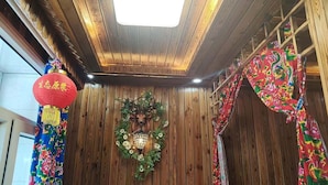 Habitació amb parets de fusta, sostre amb un òcul i una corona decorativa, i un farol vermell.