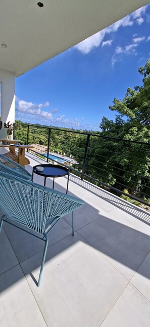 Ein Balkon mit Pool, Gartenmöbeln und Blick auf üppiges Grün.