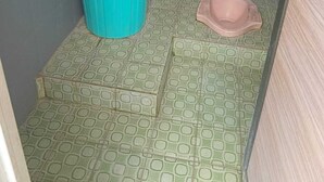 A small bathroom with a blue bucket, a pink basin, and patterned floor tiles. - Nyaman Homestay (Pare)