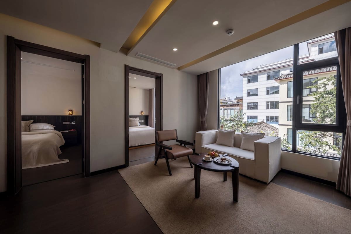 Ein modernes Hotelzimmer mit großem Fenster, einer Couch, einem Couchtisch und einem Bett.